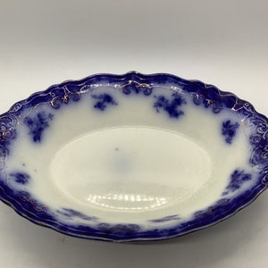 May include: A blue and white oval serving bowl with a gold rim and floral pattern.