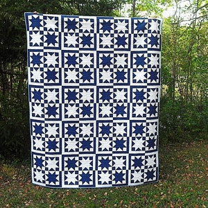 May include: A blue and white quilt with a star pattern. The quilt is made up of squares with a star in the center of each square. The stars are all the same size and shape.