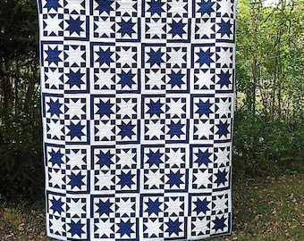 May include: A blue and white quilt with a star pattern. The quilt is made up of squares with a star in the center of each square. The stars are all the same size and shape.