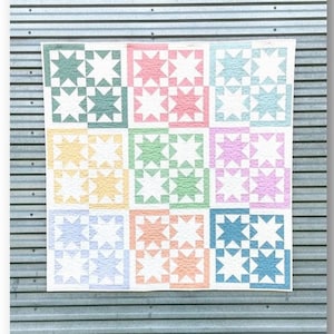 Könnte beinhalten: Ein Quiltmuster namens "Prairie Stars" von Julie Thelen quilting & design. Der Quilt besteht aus neun Blöcken, jeder mit einer anderen Pastellfarbe und einem weißen Sternmuster.
