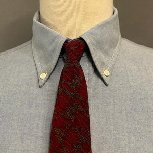 Peut inclure: Une chemise boutonnée bleu clair avec une cravate à motif rouge et marron.