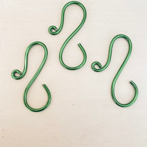 May include: Three green metal S-shaped hooks. The hooks are made of wire and have a smooth finish.