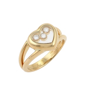 May include: A gold heart-shaped ring with a floating diamond design. The ring has a Chopard inscription on the band.