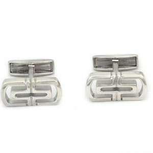 May include: A pair of silver cufflinks with a geometric design. The cufflinks are made of metal and have a polished finish.
