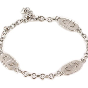 May include: A silver chain bracelet with three oval-shaped charms featuring a repeated interlocking 'G' design. The bracelet has a lobster clasp closure.