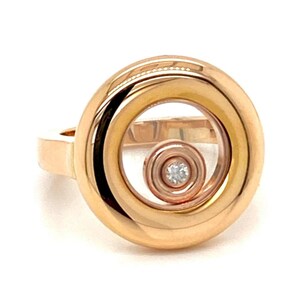 May include: A rose gold ring with a floating diamond in a clear crystal circle. The ring has a smooth, polished finish.