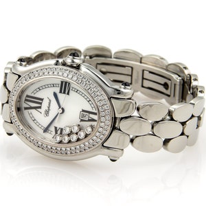 May include: A silver Chopard Happy Diamonds watch with a white mother-of-pearl dial and a diamond-encrusted bezel. The watch has a silver bracelet with a unique oval-shaped link design.