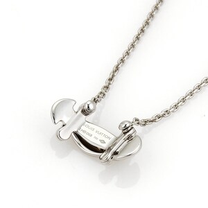 Puede incluir: Un collar de plata con un colgante de plata que dice "LOUIS VUITTON" y "M6098 750".