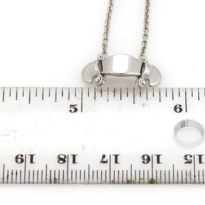 Puede incluir: Un collar de plata con un peque&ntilde;o colgante rectangular. El colgante mide aproximadamente 2,5 cm de largo y tiene una superficie lisa y pulida. El collar mide aproximadamente 45 cm de largo y tiene una cadena delicada.