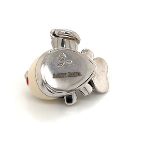 May include: Silver charm in the shape of a fish with a white and red enamel design. The back of the charm is engraved with the words "AARON BASHA".