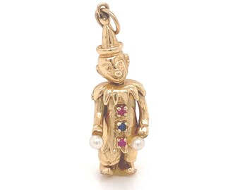 May include: A gold-toned clown charm with red, blue, and white gemstones. The clown is holding two white pearls in its hands.