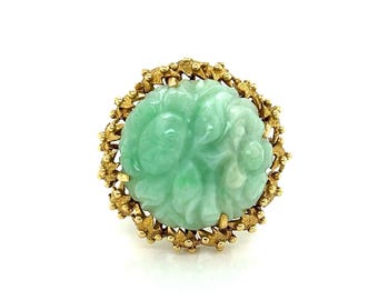May include: A green jade ring with a carved floral design set in a gold setting.