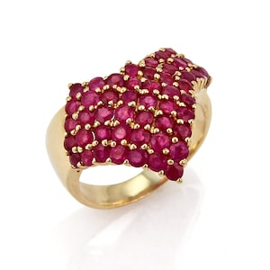 May include: A gold ring set with a cluster of red rubies. The rubies are arranged in a wave-like pattern.