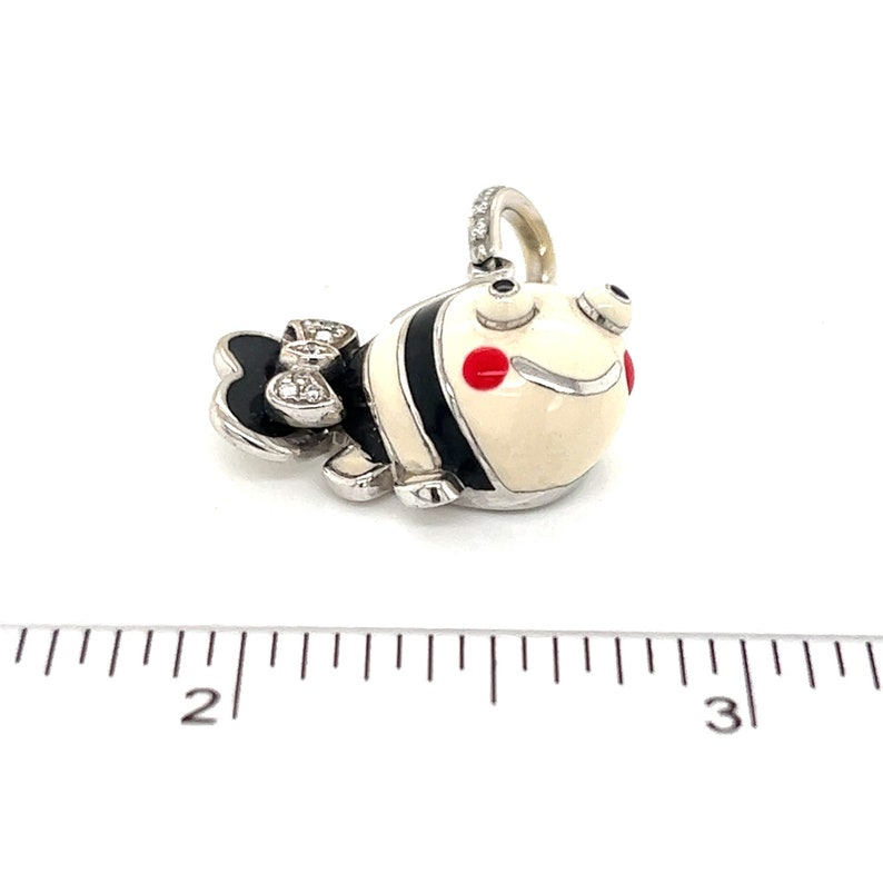 May include: A white and black enamel fish charm with red accents and diamond accents on the tail. The charm is made of silver and is about 1 inch long.