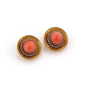 May include: A pair of gold earrings with coral cabochons. The earrings are round and have a rope-like design around the edge.