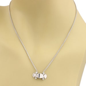 Puede incluir: Un collar de cadena de plata con un peque&ntilde;o colgante de monopat&iacute;n de plata.
