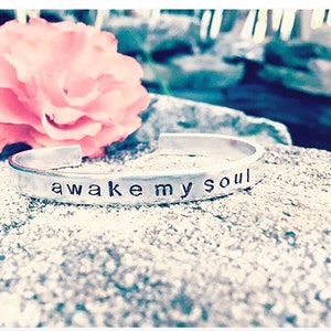 May include: Silver bracelet with the words "awake my soul" engraved on it.