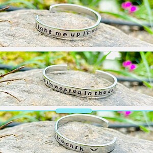 May include: Silver bracelet with the words "light me up i'm wasted in the dark" engraved on it.