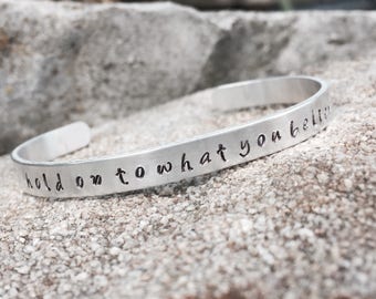 Pulsera de aluminio estampado inspirada en la mano de Mumford & Sons con la letra "hold on to what you believe"