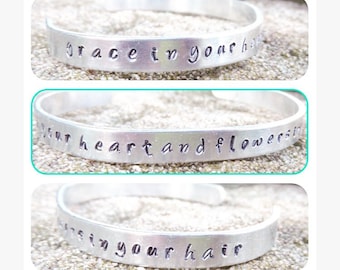Brazalete de aluminio estampado a mano de Mumford & Sons con la letra "Gracia en tu corazón y flores en tu cabello".