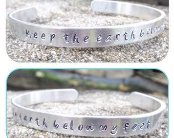 Pulsera de aluminio estampada a mano con la letra de Mumford and Sons "mantén la tierra bajo mis pies".