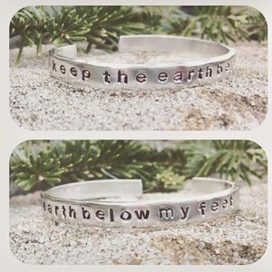 May include: Silver bracelet with the words "keep the earth below my feet" engraved on it.
