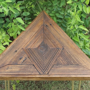 May include: A triangular wooden table with a geometric pattern on the top. The table is made of reclaimed wood and has a rustic finish.