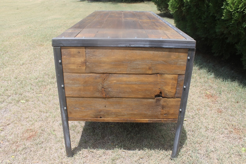 May include: A rustic wooden desk with a metal frame and legs. The desk has a natural wood finish and is made of reclaimed wood. The metal frame is painted a dark gray color.