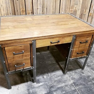 May include: A rustic wooden desk with metal accents and three drawers. The desk has a dark wood finish and metal legs.