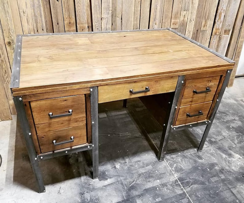 May include: A rustic wooden desk with metal accents and three drawers. The desk has a dark wood finish and metal legs.