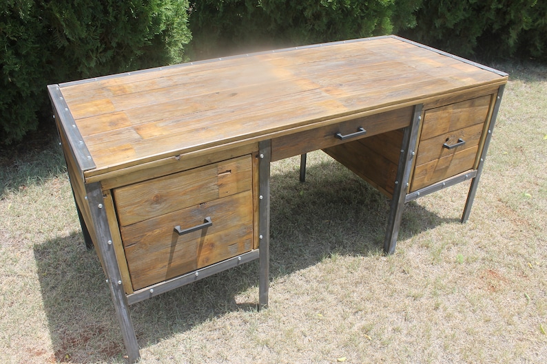 May include: A rustic wooden desk with metal accents and two drawers on each side. The desk has a distressed wood finish and black metal legs.