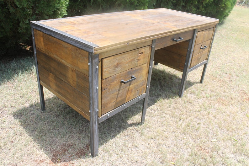 May include: A rustic wooden desk with metal accents and two drawers. The desk has a natural wood finish and black metal legs and drawer pulls.