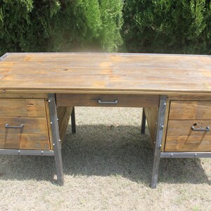 May include: A rustic wooden desk with metal accents and drawers. The desk has a natural wood finish and features metal legs and drawer pulls.