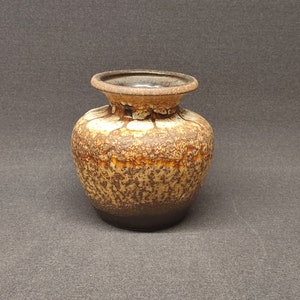 May include: A small, brown and white ceramic vase with a speckled glaze.