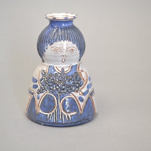Puede incluir: Un jarrón de cerámica azul y blanco con forma de persona con una cara estilizada y un patrón floral.