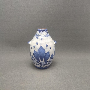 Könnte beinhalten: Eine kleine weiße Keramikvase mit blauen Blumendesigns und zwei kleinen Griffen an den Seiten.