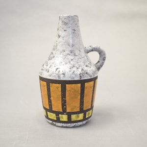 Könnte beinhalten: Eine weiße Keramikvase mit einem braunen und goldenen geometrischen Muster. Die Vase hat einen runden Körper und einen kleinen Henkel.