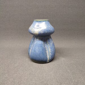 Puede incluir: Un pequeño jarrón de cerámica azul y blanco con un esmalte texturizado. El jarrón tiene una boca ancha y una base estrecha.