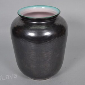 May include: A black ceramic vase with a green and pink rim. The vase has a textured, ribbed surface.