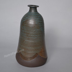 Peut inclure: Un vase en céramique avec un glaçage brun et vert. Le vase a une base large et un col étroit. C'est une pièce unique et décorative.