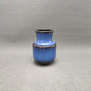 Könnte beinhalten: Eine kleine, blaue Keramikvase mit dunkelblauer Glasur. Die Vase hat einen runden Körper und einen schmalen Hals.