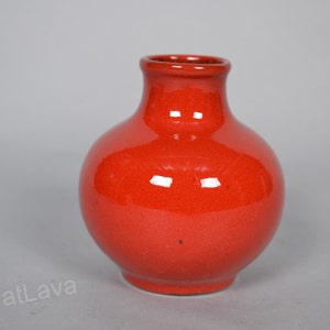 May include: A small, round, red ceramic vase with a glossy finish.