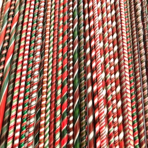 May include: A close-up of a collection of colorful candy canes. The candy canes are red, white, green, and brown, with a twisted, striped design. The image is a close-up, showing the details of the candy canes.