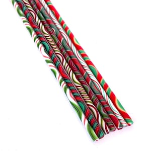 Può includere: Una collezione di bastoncini di zucchero colorati con strisce rosse, verdi e bianche. I bastoncini sono disposti diagonalmente su uno sfondo bianco, mostrando il loro design festivo.