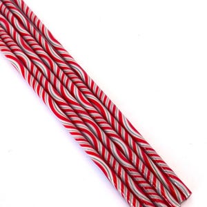 Könnte beinhalten: Nahaufnahme von mehreren rot, weiß und grau gestreiften Zuckerstangen. Die Stäbe sind diagonal vor einem weißen Hintergrund angeordnet. Die Zuckerstangen haben eine glänzende Oberfläche, wahrscheinlich ein festlicher Leckerbissen.