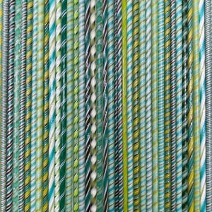 May include: A collection of colorful glass rods in various shades of green, blue, yellow, and white. The rods are twisted and swirled, creating a striped pattern. The rods are arranged vertically, filling the frame.