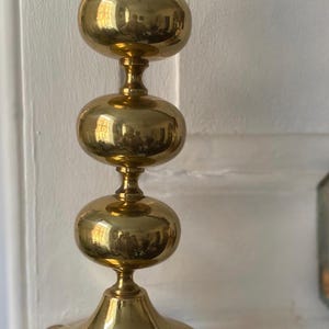 Può includere: Una lampada da tavolo vintage in ottone con un design impilato a forma di sfera. La lampada ha una finitura lucida, una base rotonda e un portalampada standard. Il cavo è visibile e la lampada è posta su uno sfondo bianco.