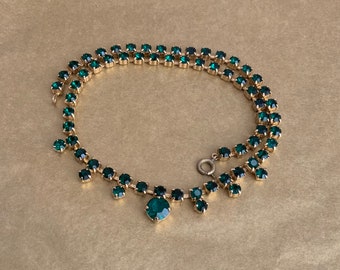 May include: A double strand emerald green rhinestone necklace with a teardrop pendant.