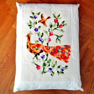 May include: White rectangular pillow with a colorful embroidered peacock design. The peacock has an orange and red body with a long, vibrant tail. The design includes a bird, flowers, and green leaves.