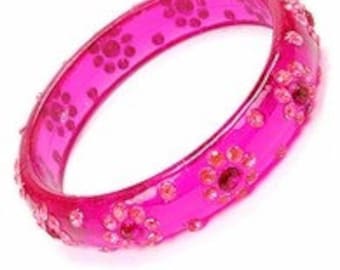 May include: A pink plastic bangle bracelet with a floral design and clear rhinestones.